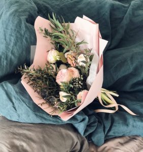 pink and green flower bouquet on bed sheet