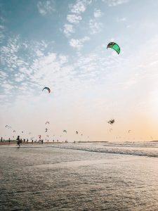 a group of people flying kites on the beach